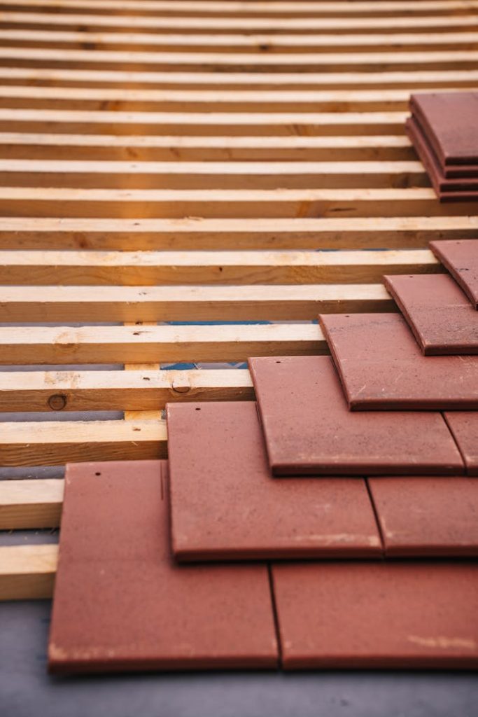 roof-construction-with-red-tiles-and-wooden-framework-31763538 Red roofing tiles and wooden framework in progress on a building roof.